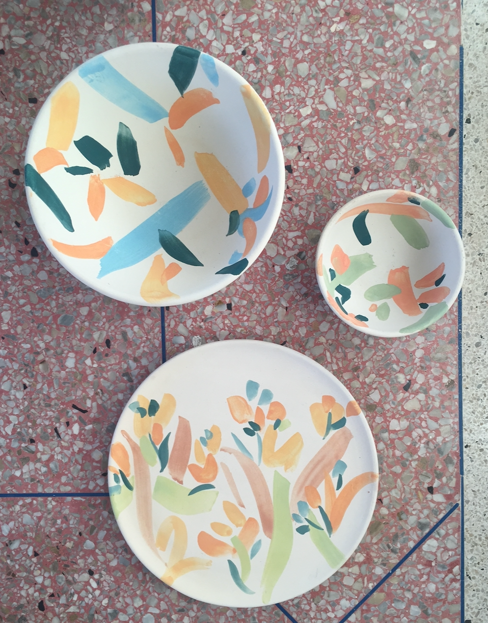Three hand-painted ceramic pieces on patterned tiles