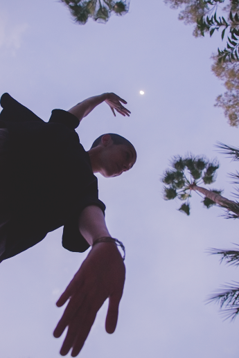 Figure reaching beneath a twilight sky